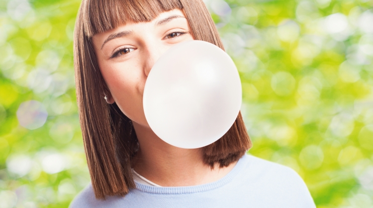 girl doing a bubble with a chewing gum on a white background